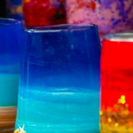 Colorful hand-painted glass candle holders with abstract designs.