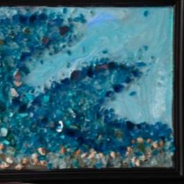 Framed artwork depicting a blue ocean wave on a shelf.